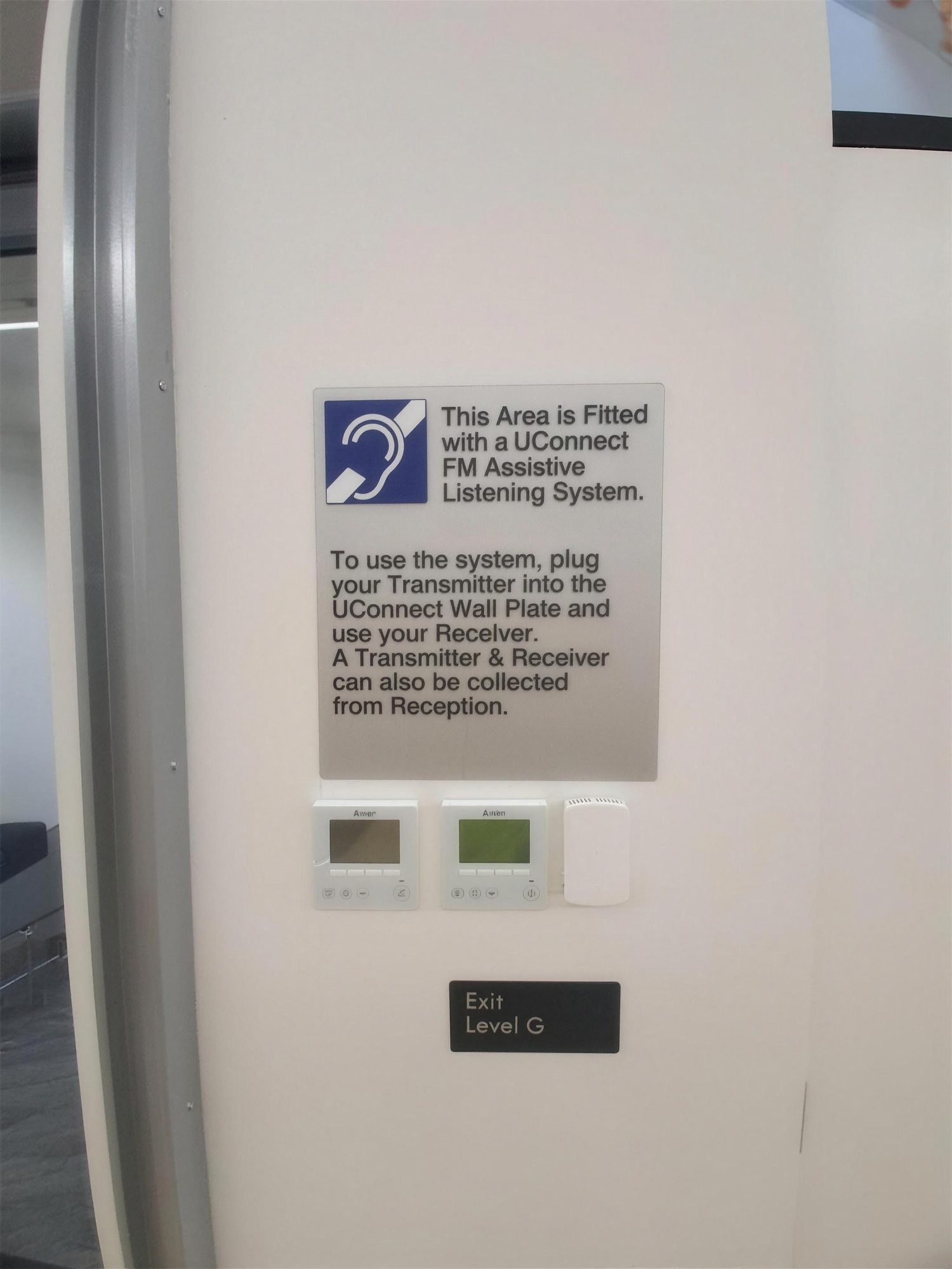 Assistive listening system sign beside wall controls
